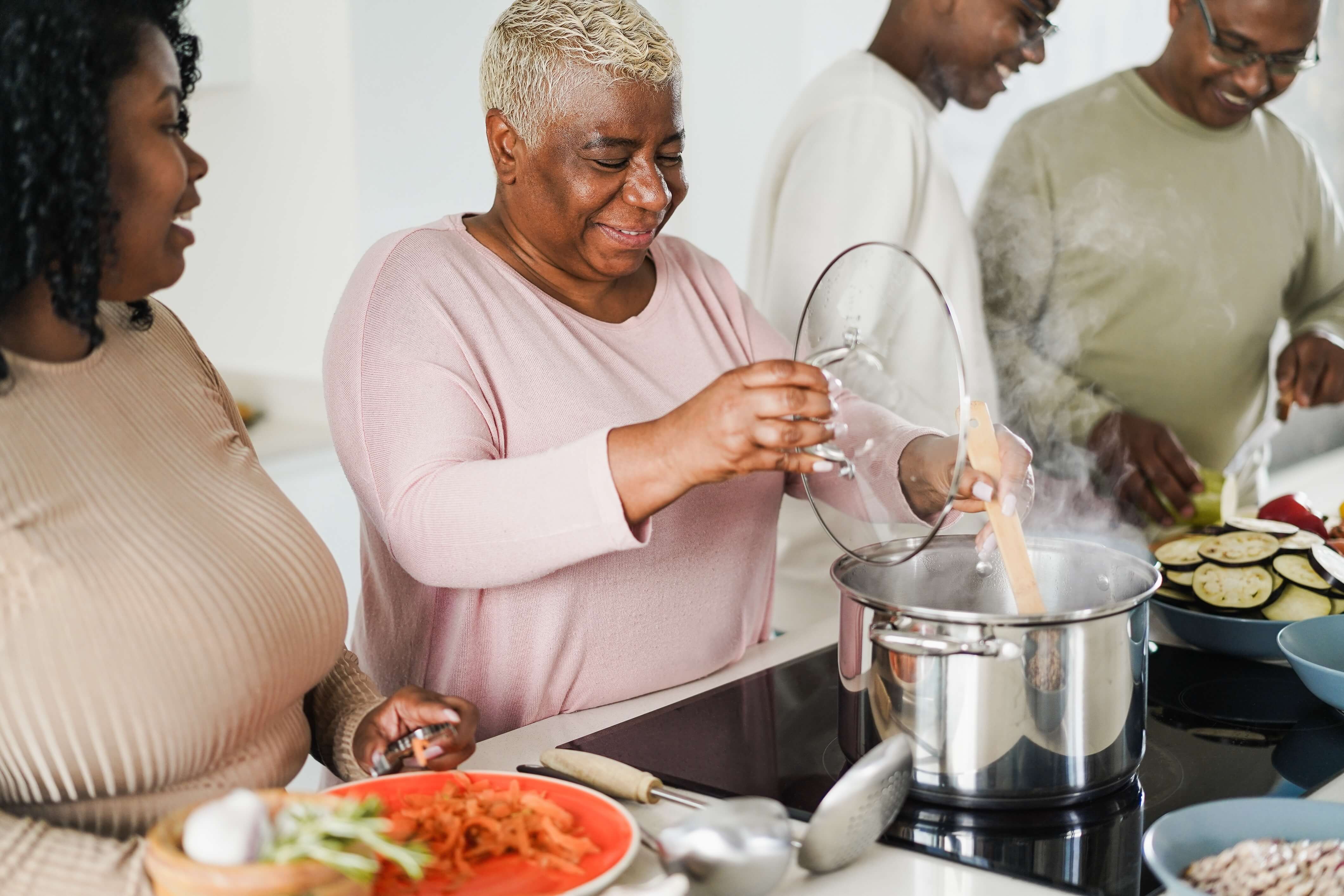 two women and two men cooking together on a stove top two women and two men cooking together on a stove top