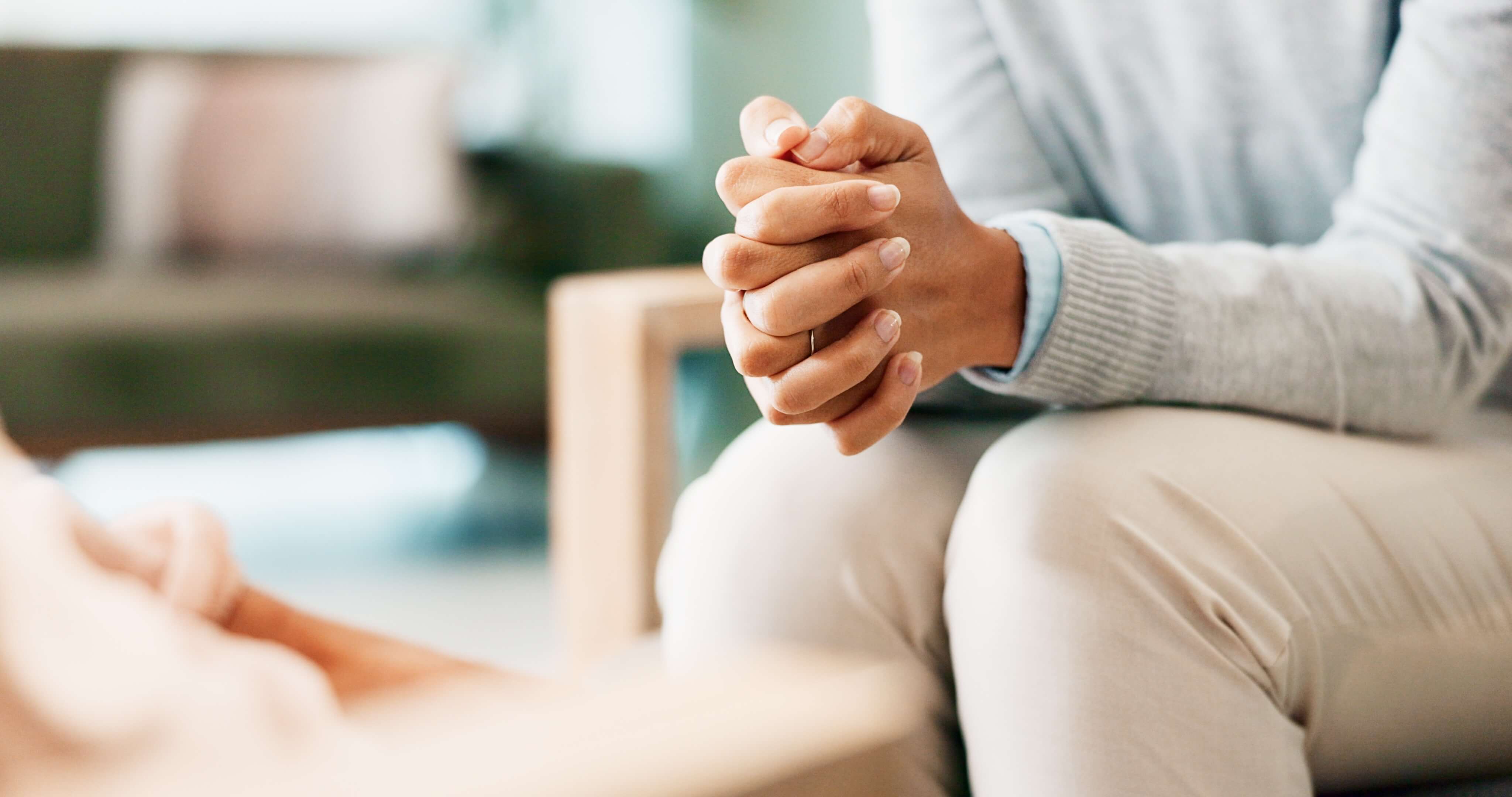 image of a person sitting with hands clasped together