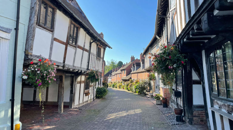 Narrow road with white and black houses on either side Narrow road with white and black houses on either side