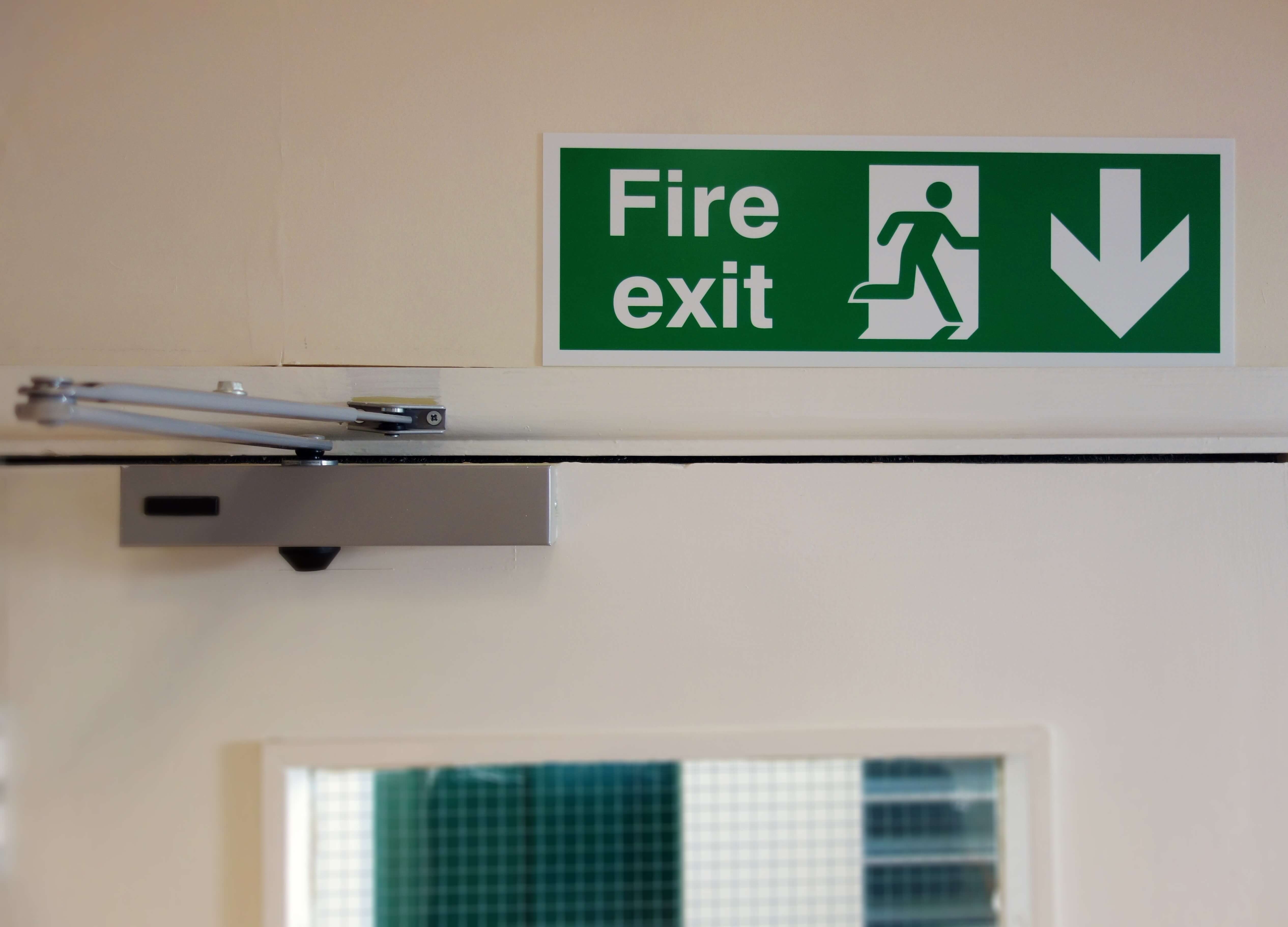 green fire exit sign above a exit door