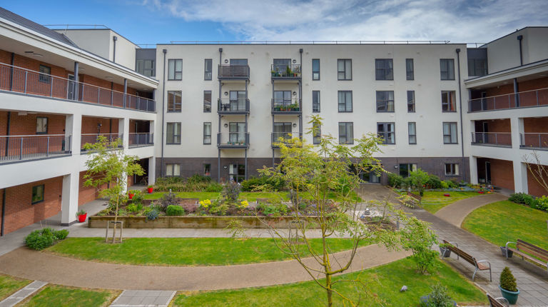 U-shaped apartment block with a lawn with trees, pathways and benches in the centre of the building U-shaped apartment block with a lawn with trees, pathways and benches in the centre of the building