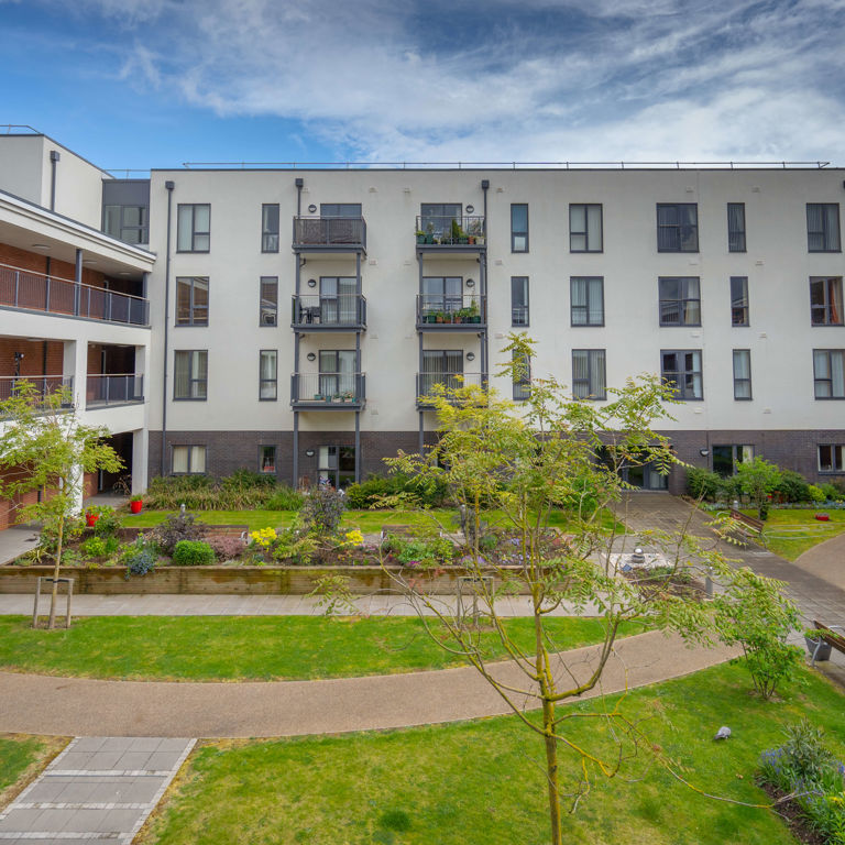 U-shaped apartment block with a lawn with trees, pathways and benches in the centre of the building U-shaped apartment block with a lawn with trees, pathways and benches in the centre of the building