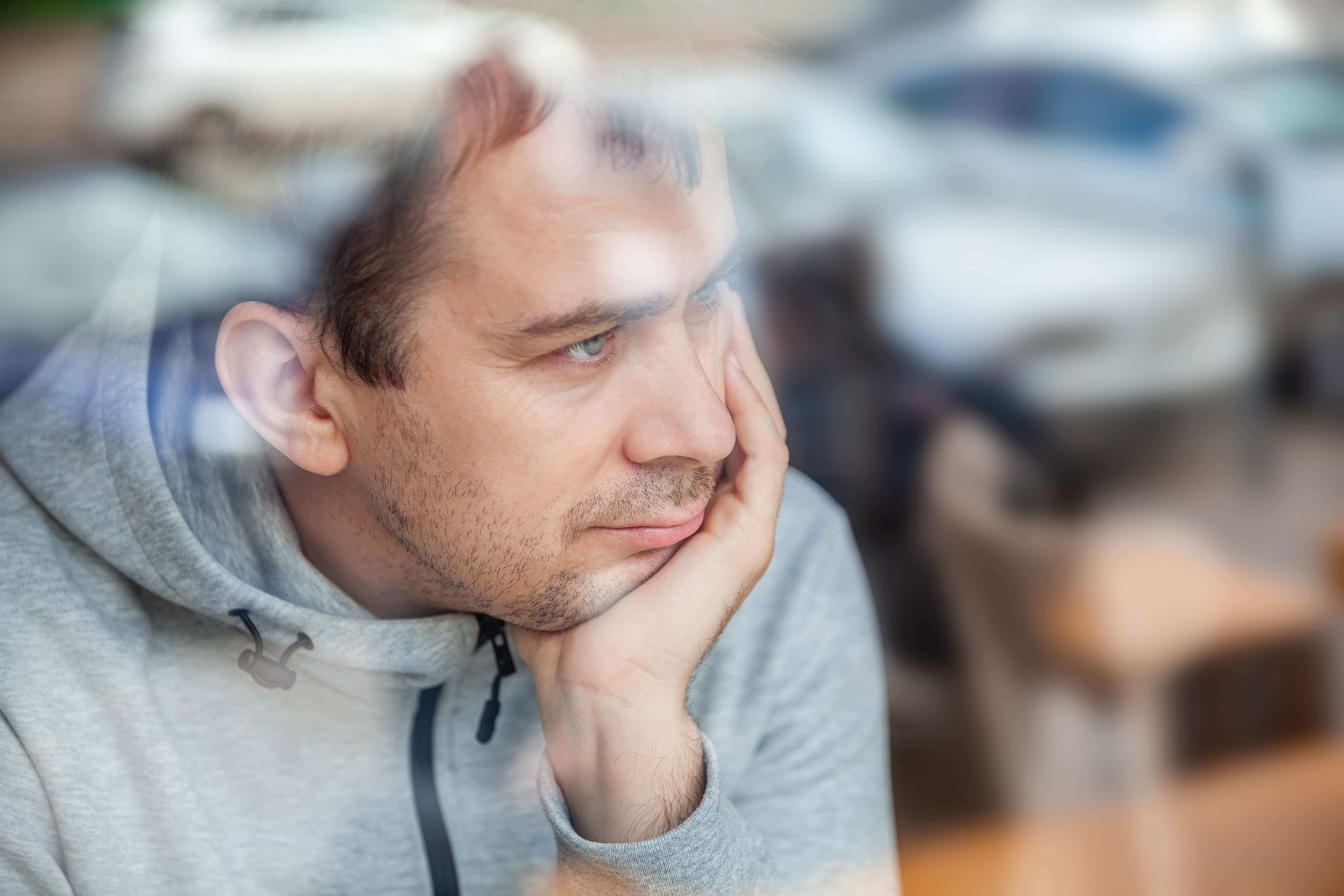 man in grey sweater looking out of window man in grey sweater looking out of window