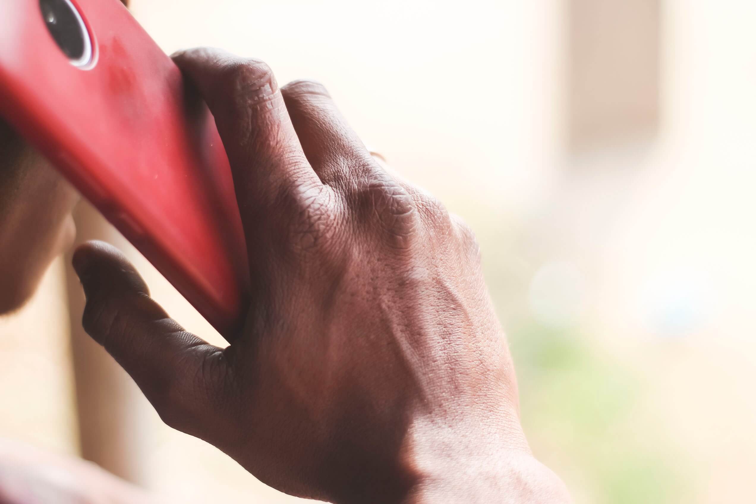 man holding a red phone to his ear making a call