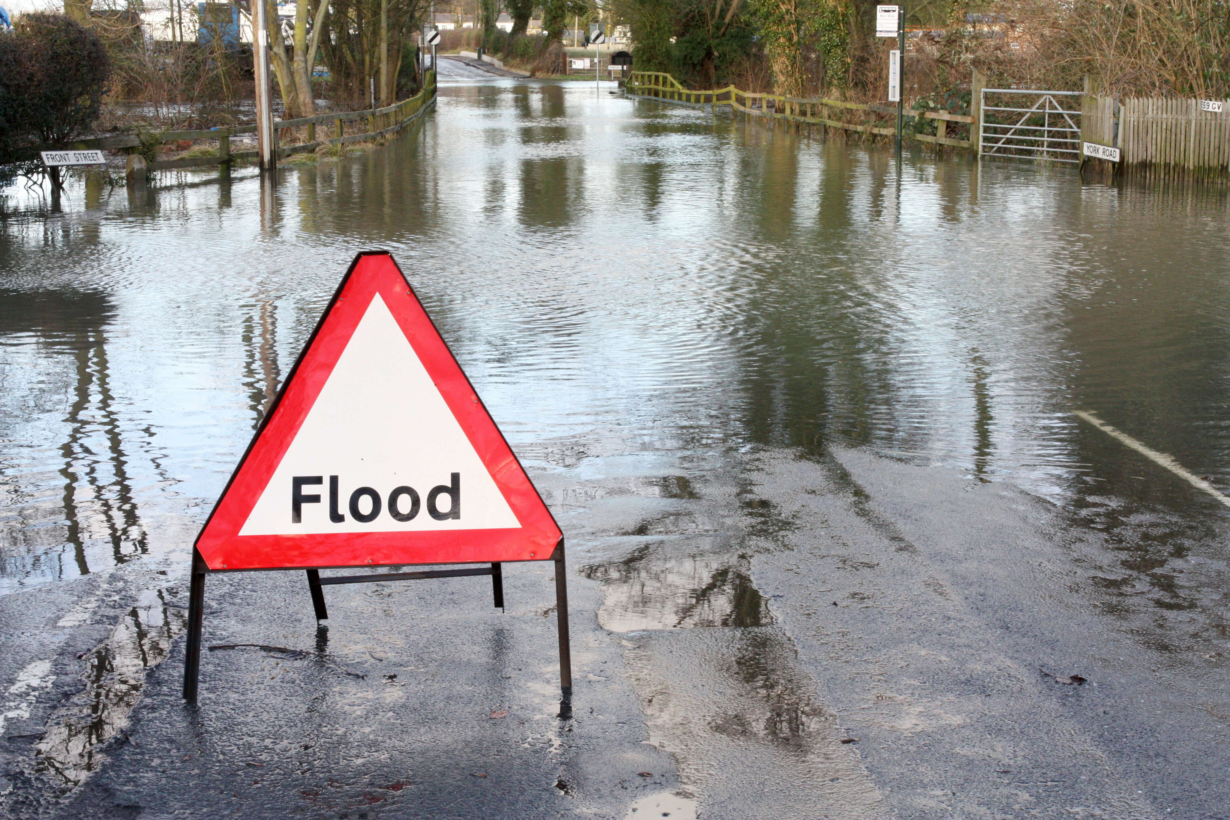 red and white flood sign in water on flooded road