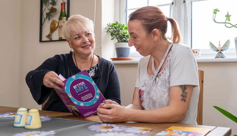 two ladies looking at a Better Days booklet two ladies looking at a Better Days booklet