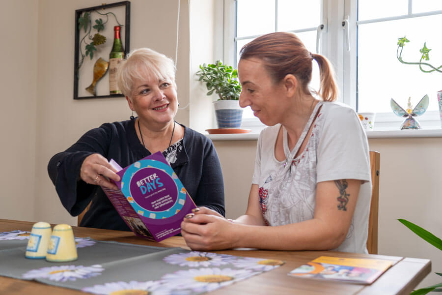 two ladies looking at a Better Days booklet two ladies looking at a Better Days booklet