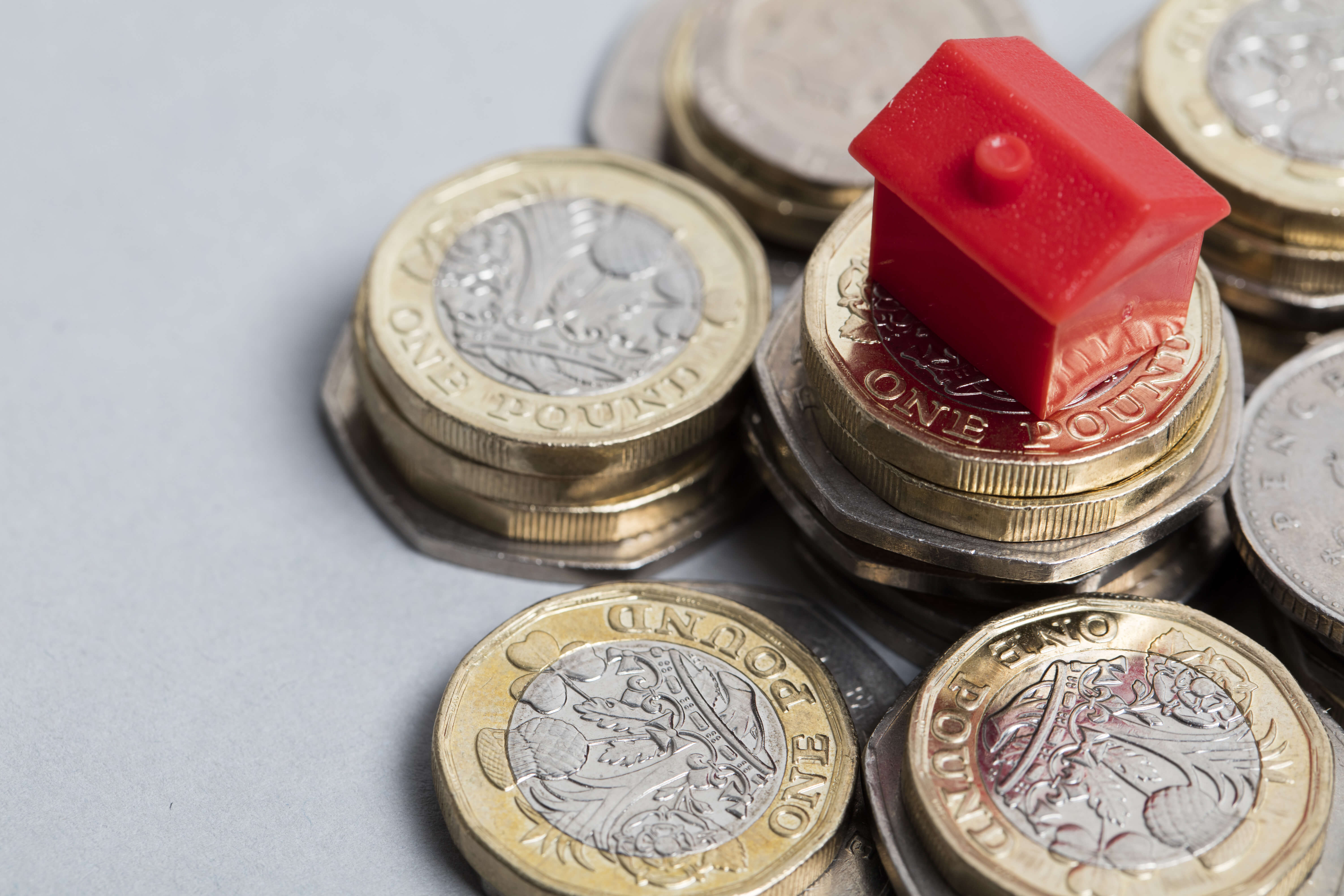 red monopoly house on a pile of coins red monopoly house on a pile of coins