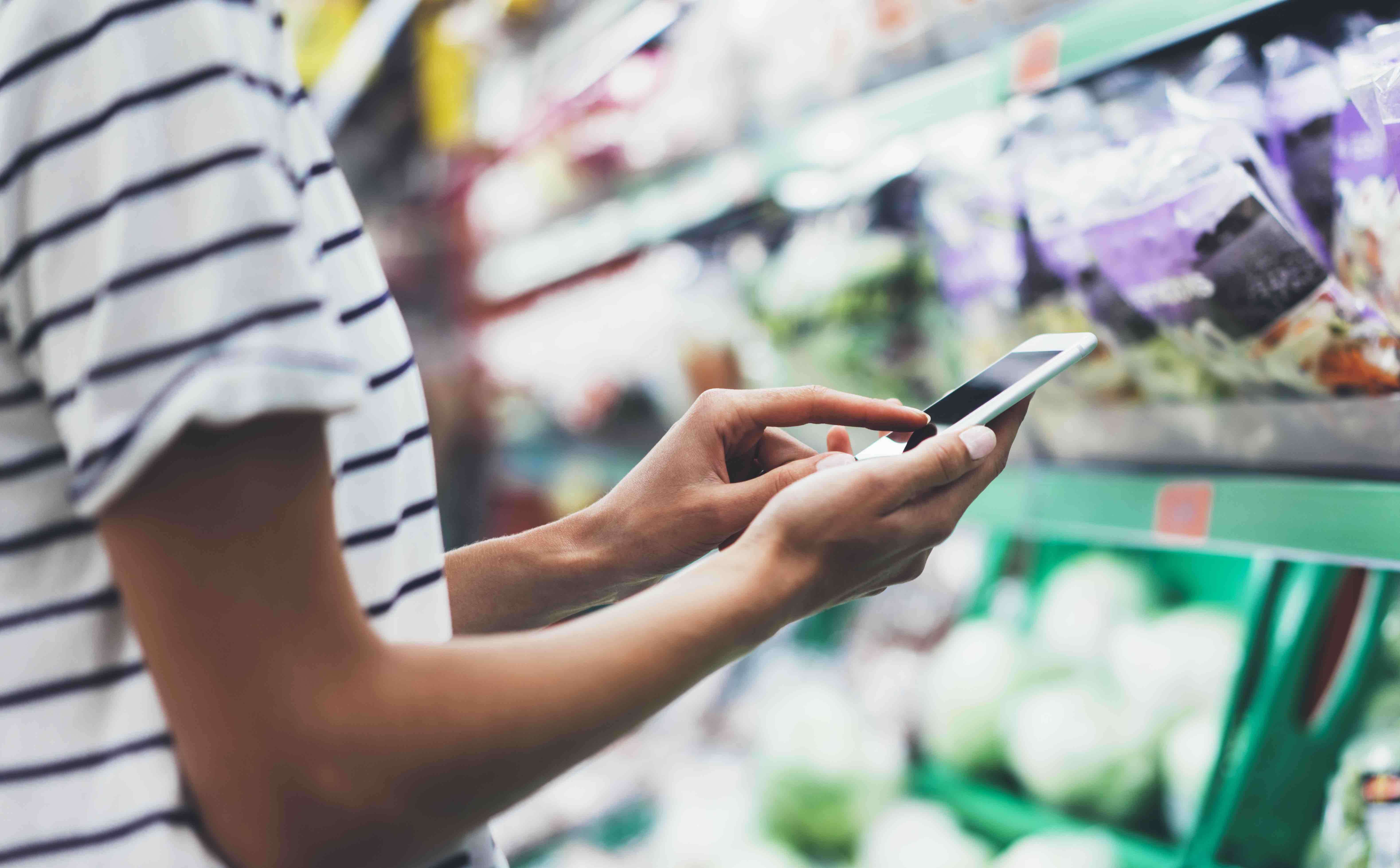 lady looking at a shopping list on her mobile phone in a grocery store