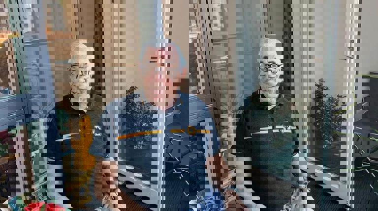 Older gentleman sitting on a chair at the glass table on his house patio Older gentleman sitting on a chair at the glass table on his house patio