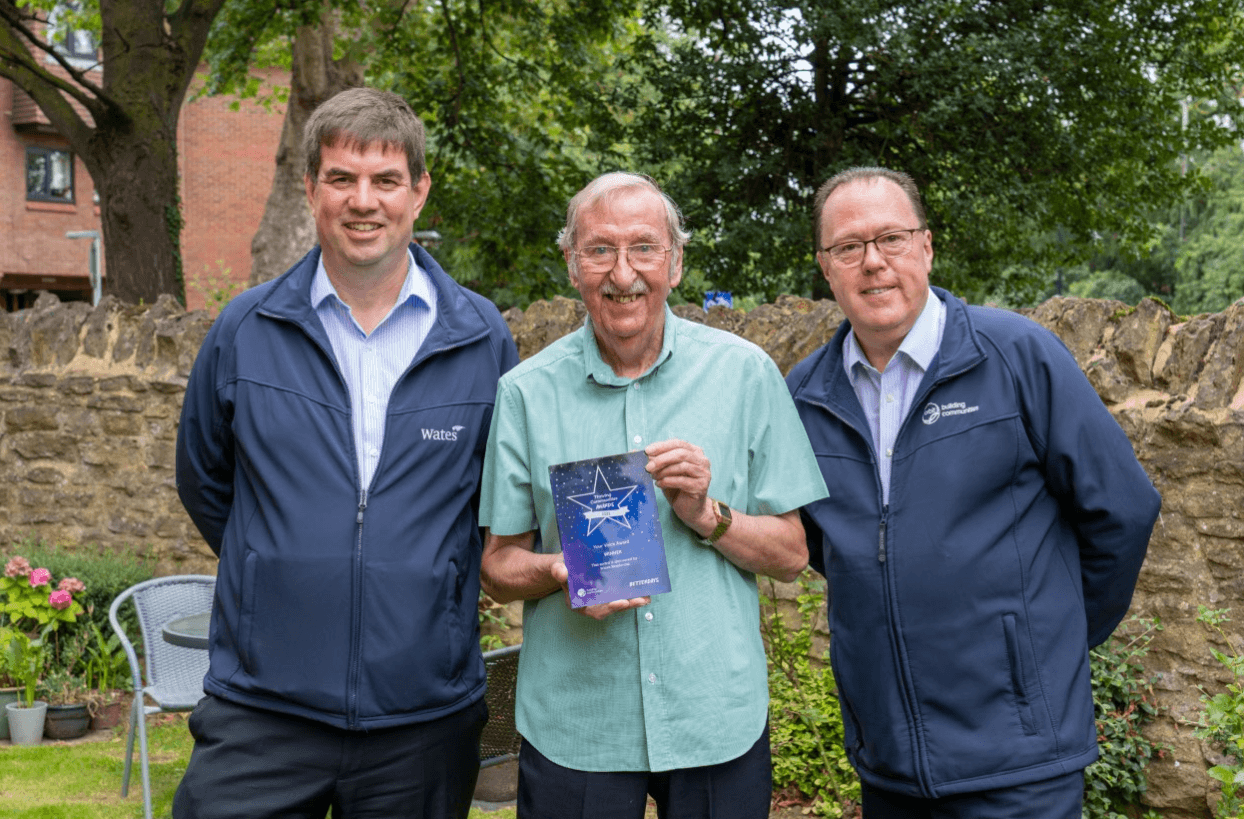 man standing next to another two men holding a thriving communities award man standing next to another two men holding a thriving communities award