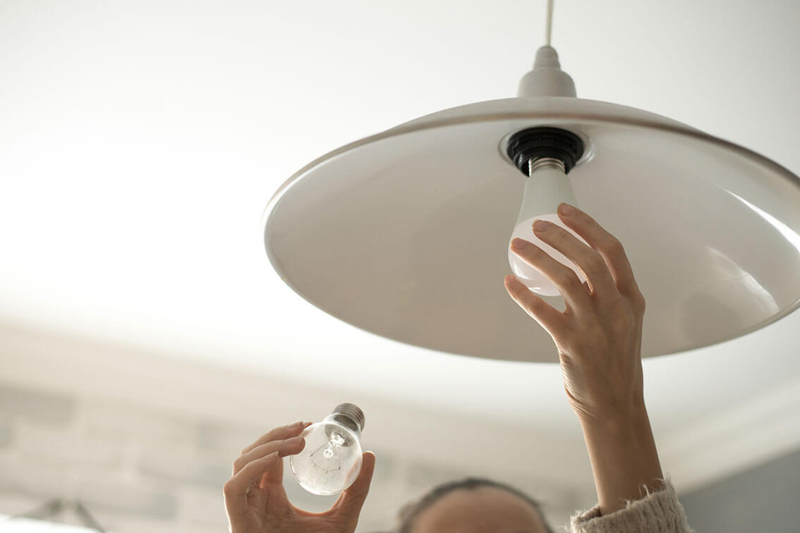 hands changing a lightbulb on a light on the roof