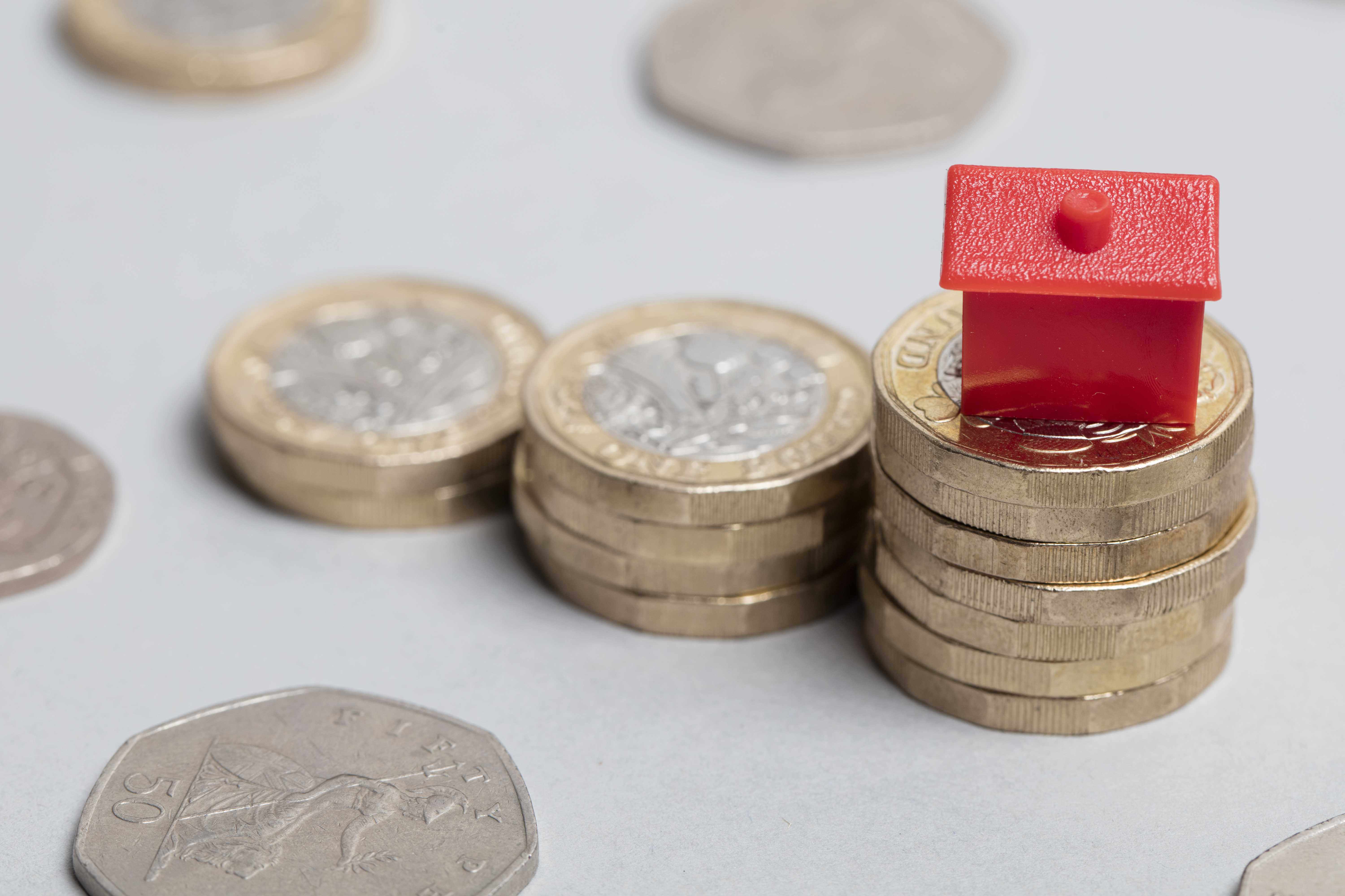 Pound coins stacked with a plastic red house on top