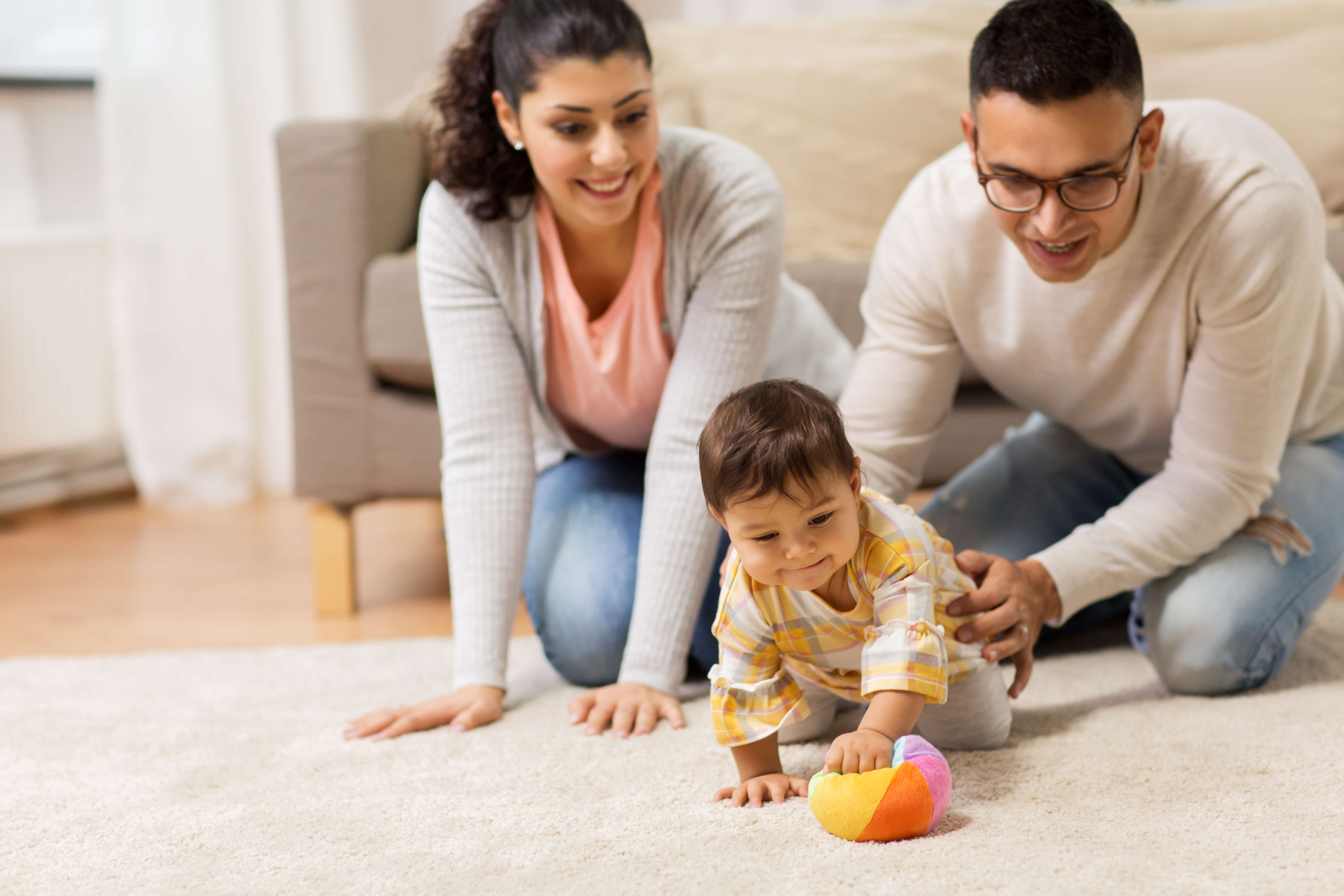 couple kneeling on floor with a crawling baby