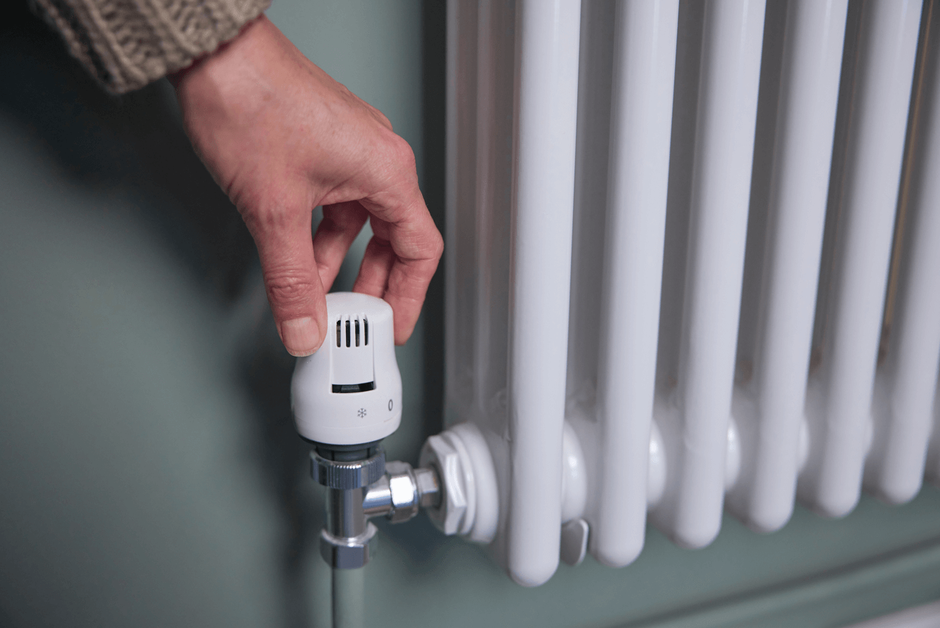 hand turning up temperature on a heater