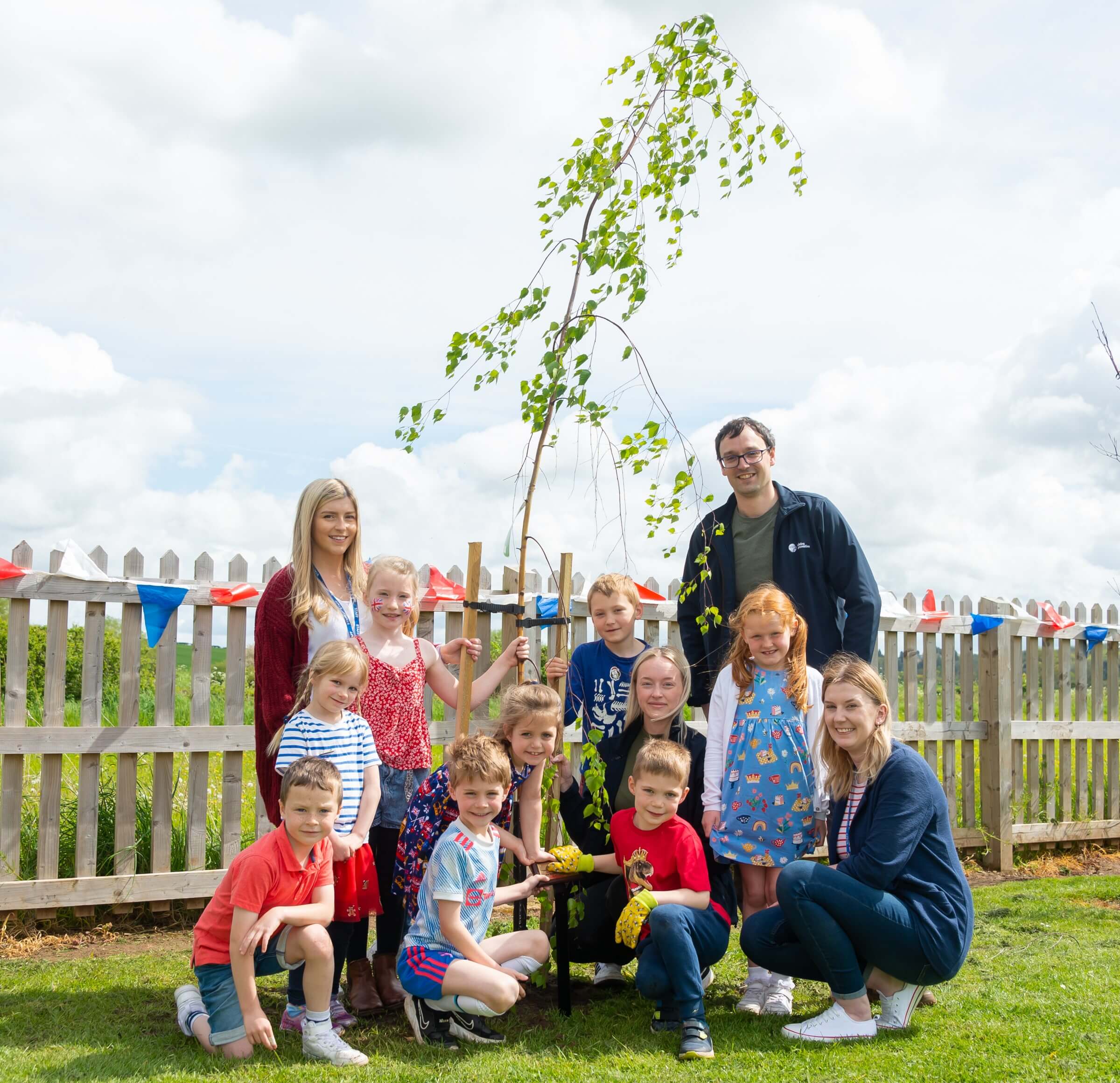 group of children standing in front of a tree they planted