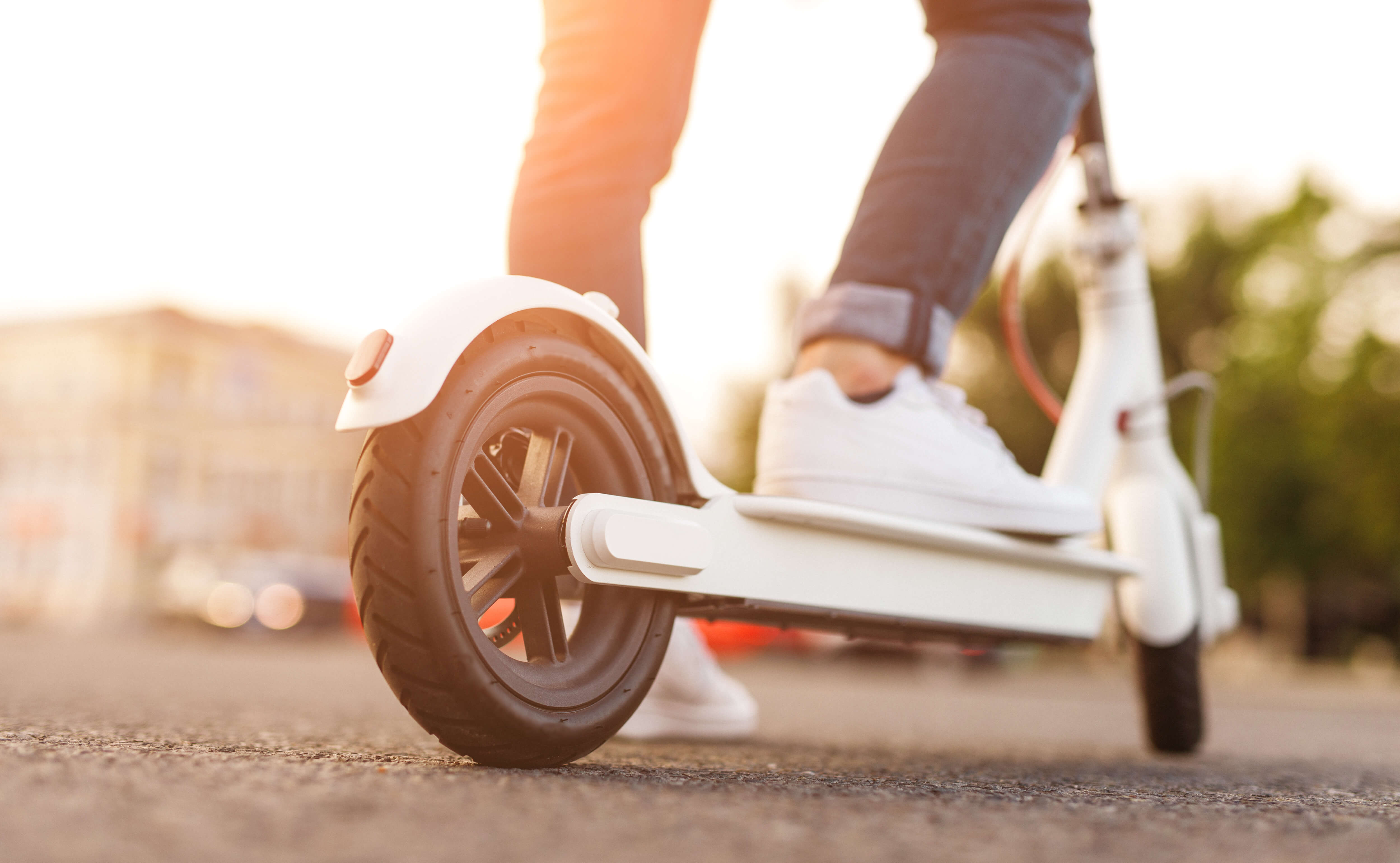 feet wearing white sneakers riding a white electric scooter feet wearing white sneakers riding a white electric scooter