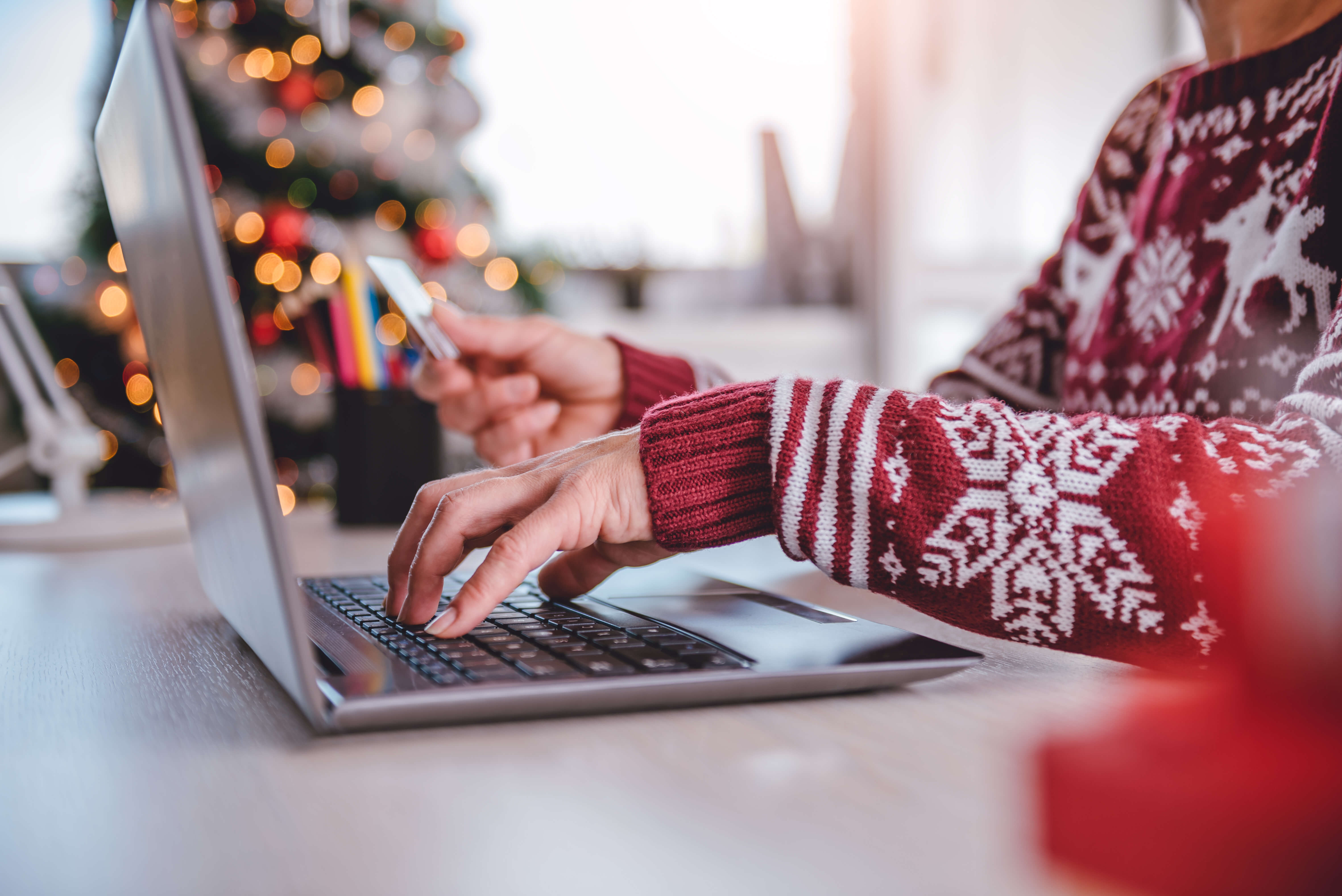 person wearing a Christmas jumper typing on a laptop