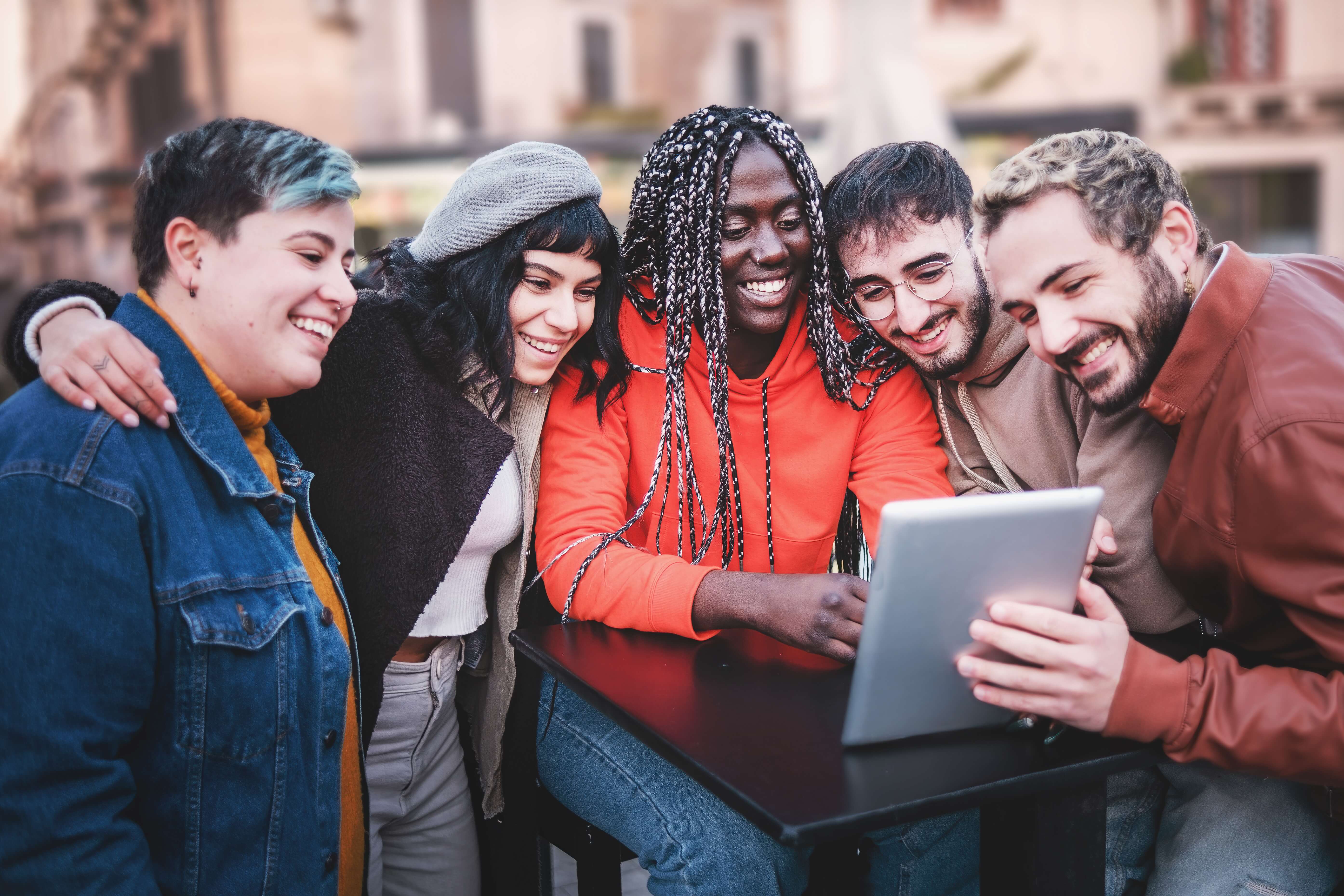 group of friends looking at a tablet and smiling group of friends looking at a tablet and smiling