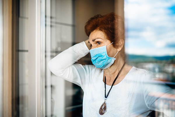 lady standing by window wearing a blue mask